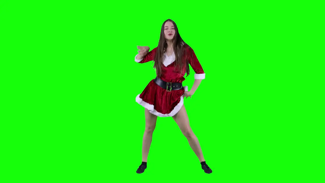 Female dancer in Santa costume on New Year indoor studio party dancing in front of green screen excited woman and energetic chroma key