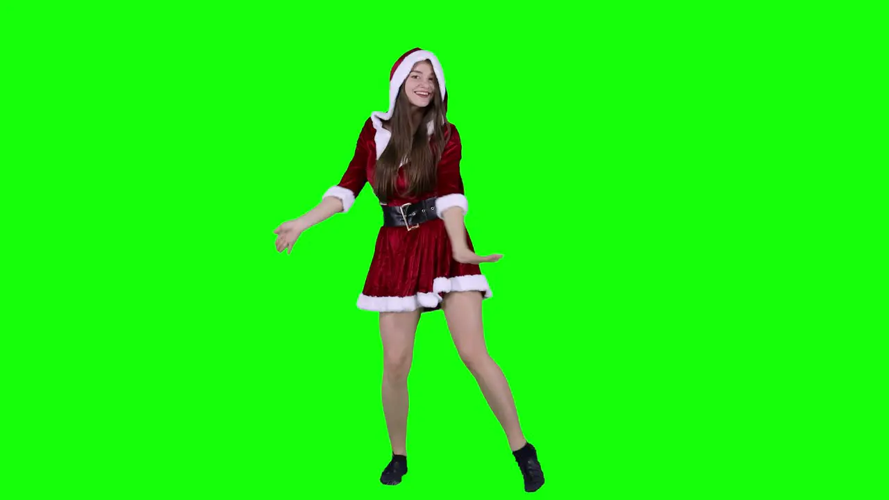 Happy woman 20s in red dress Santa Christmas dancing fooling around having fun expressive gesticulating hands isolated on green screen background studio