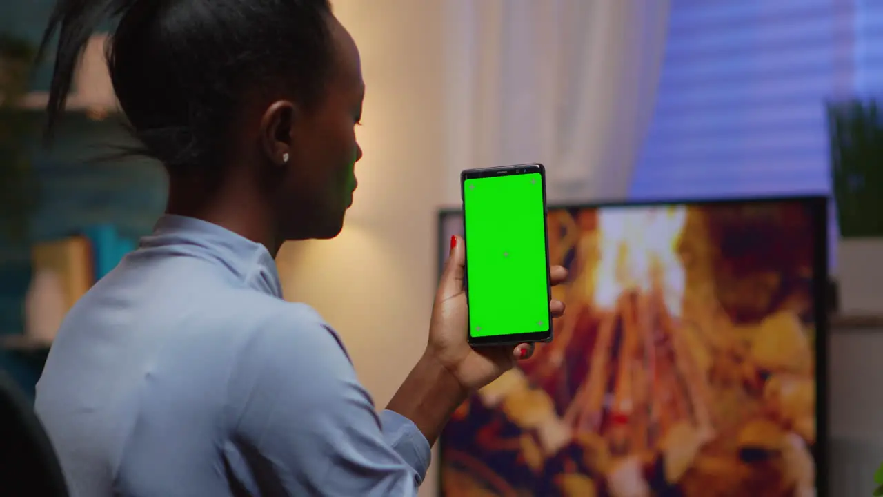 Lady looking at green screen smartphone while relaxing at home