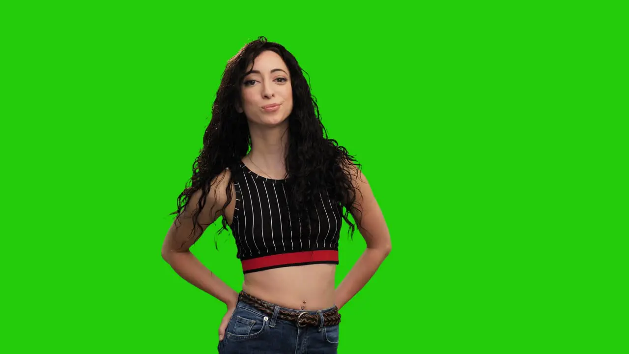 Beautiful fit female holds hands in pockets and turns on green screen