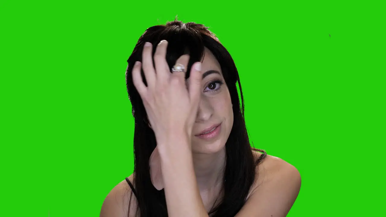 Portrait of beautiful brunette woman adjusting hair on green screen