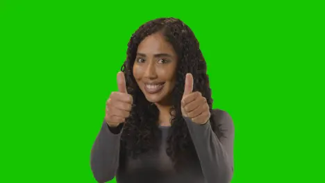 Studio Portrait Shot Of Woman Giving Double Thumbs Up Sign Against Green Screen