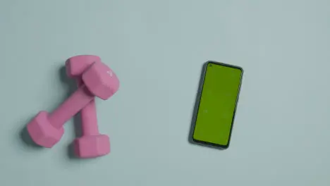 Overhead Fitness Studio Shot Of Male Hand Picking Up Exercise Dumbbell Weights Next To Green Screen Mobile Phone 2