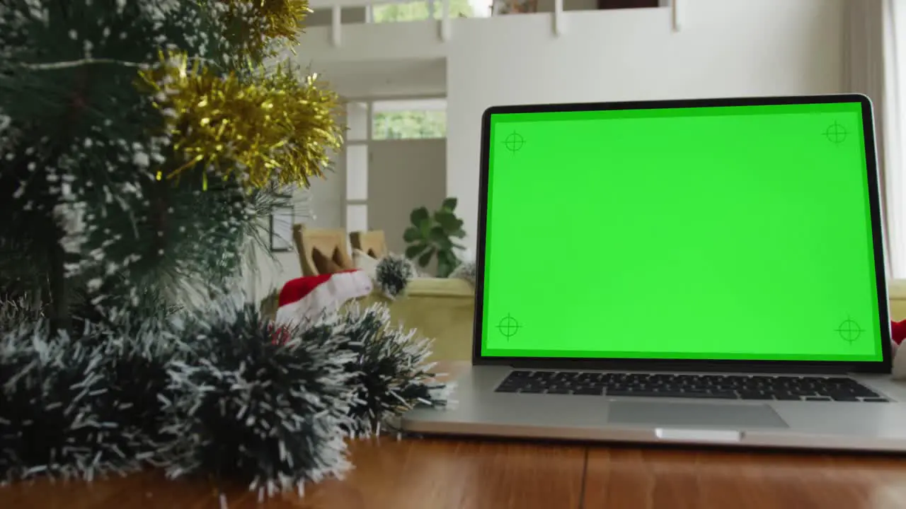 Laptop with green screen copy space on table at home with decorated christmas tree