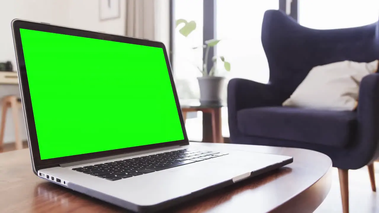 Laptop with green screen on coffee table in sunny living room slow motion