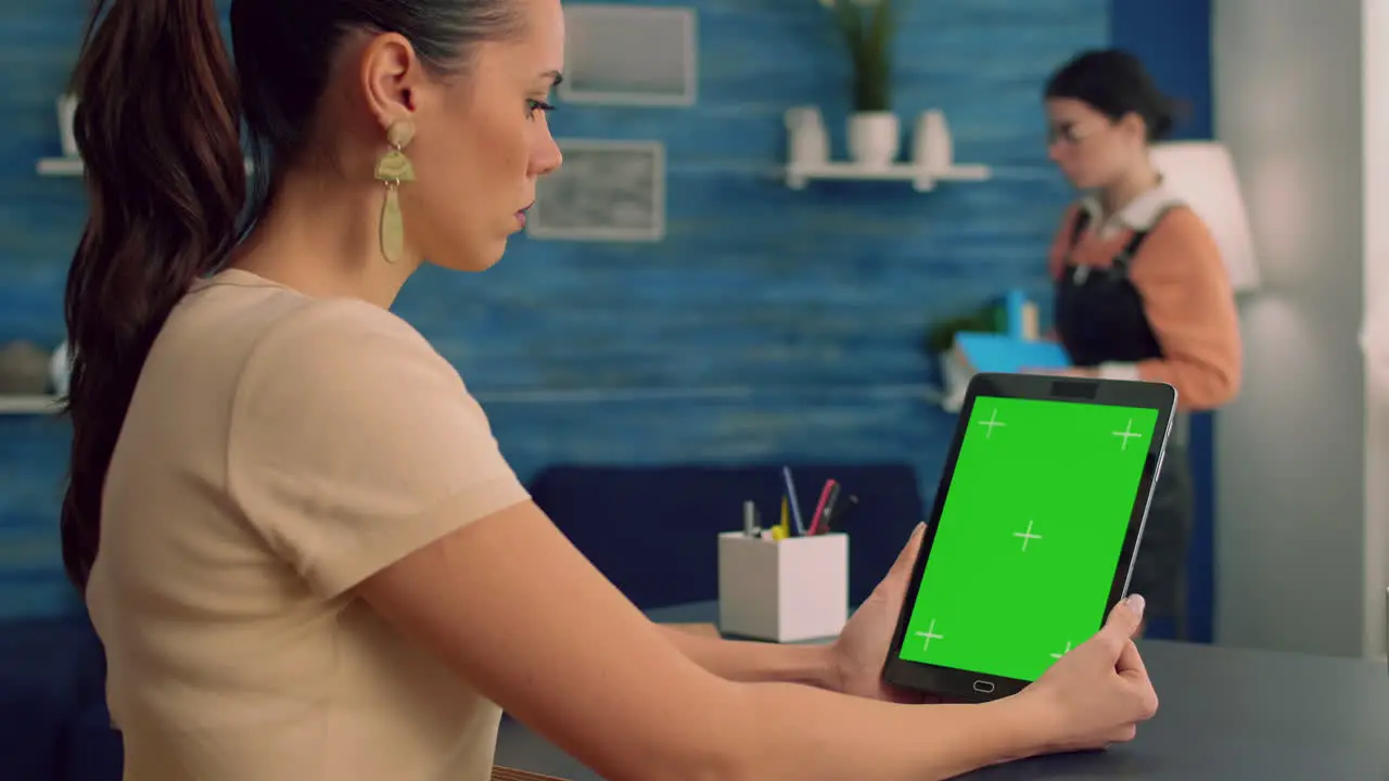 Freelancer holding tablet computer with mock up green screen chroma key display