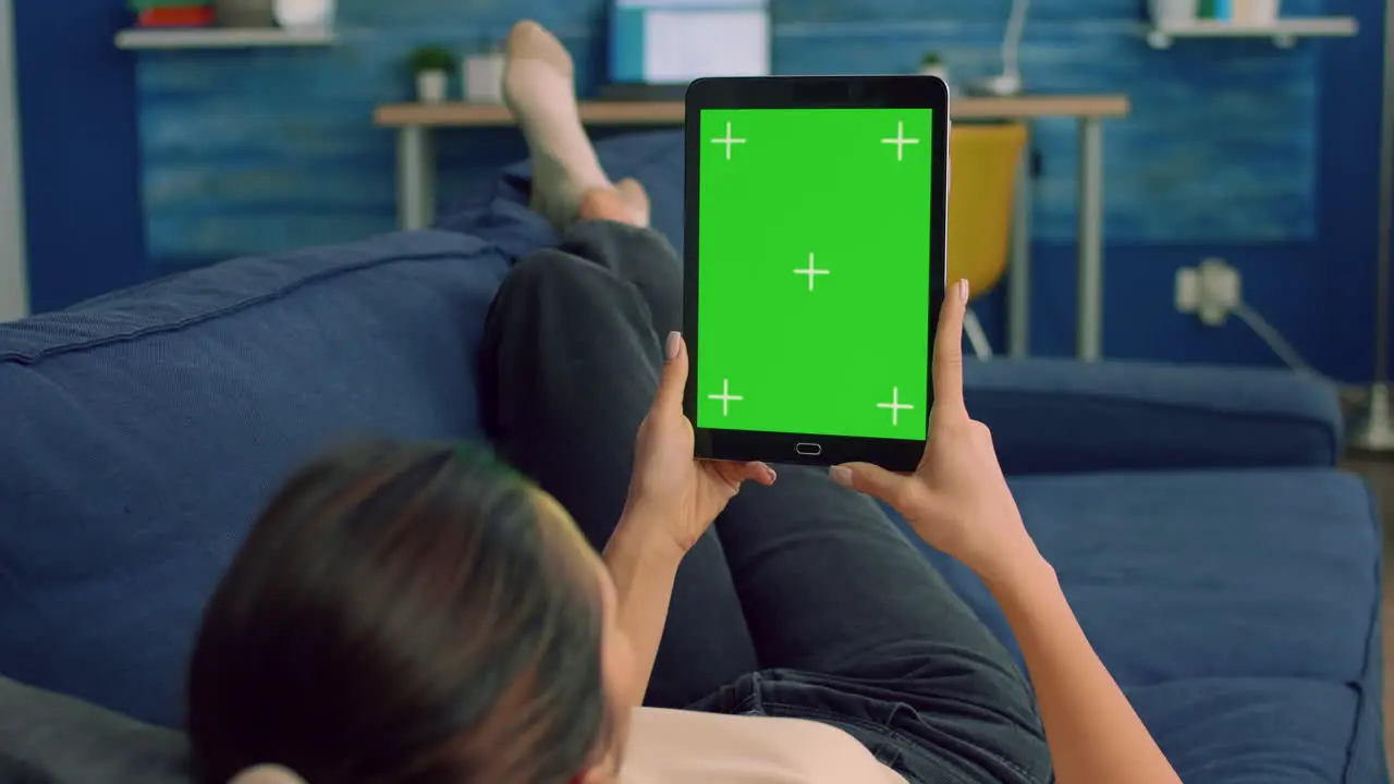 Casual woman lying on sofa using tablet computer mock up green screen