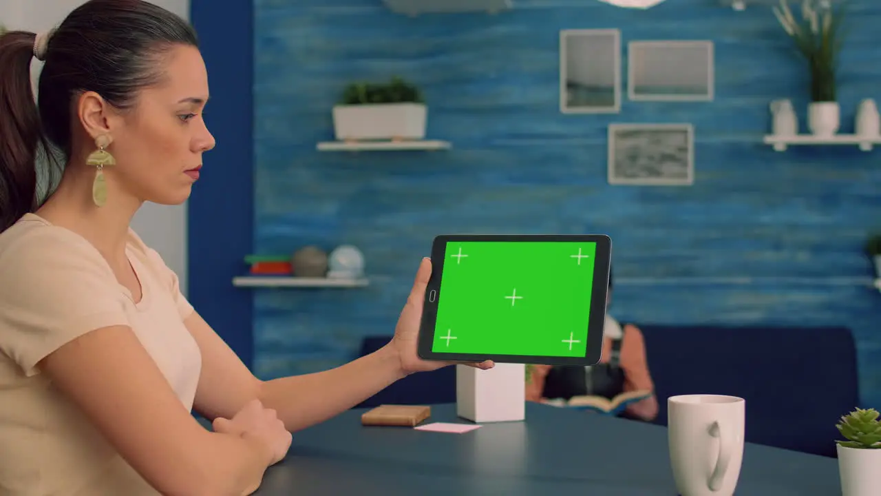 Caucasian female looking at tablet computer with mock up green screen for online advertising