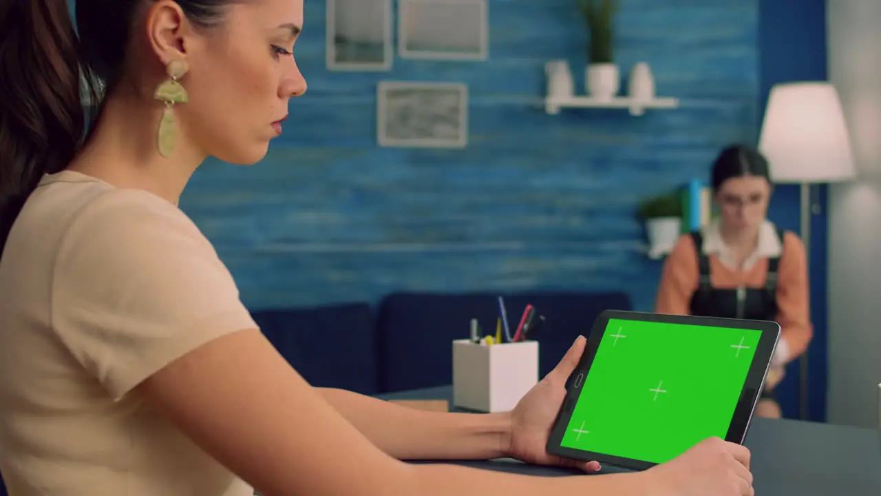 Freelancer reading online book using tablet computer with mock up green screen display