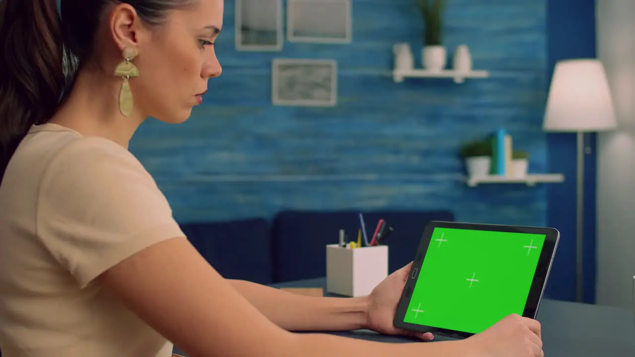 Woman working at office desk using mock up green screen tablet computer