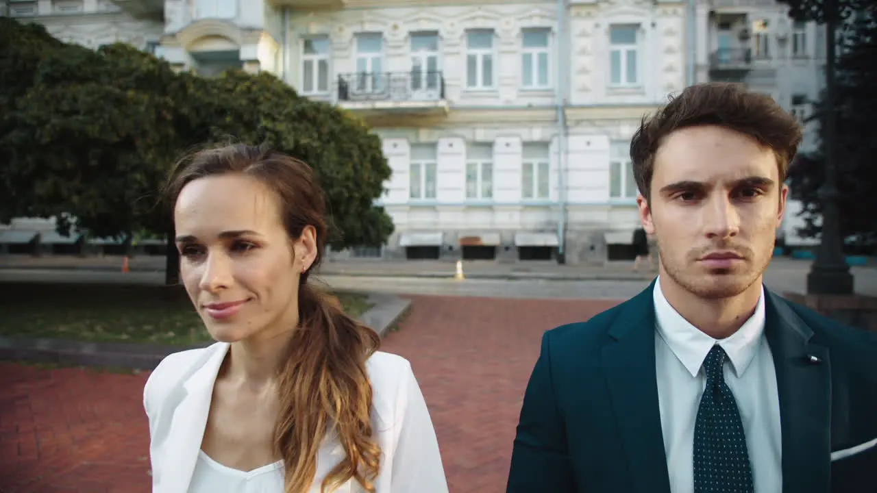 Smiling lady and business man looking each other walking in city center