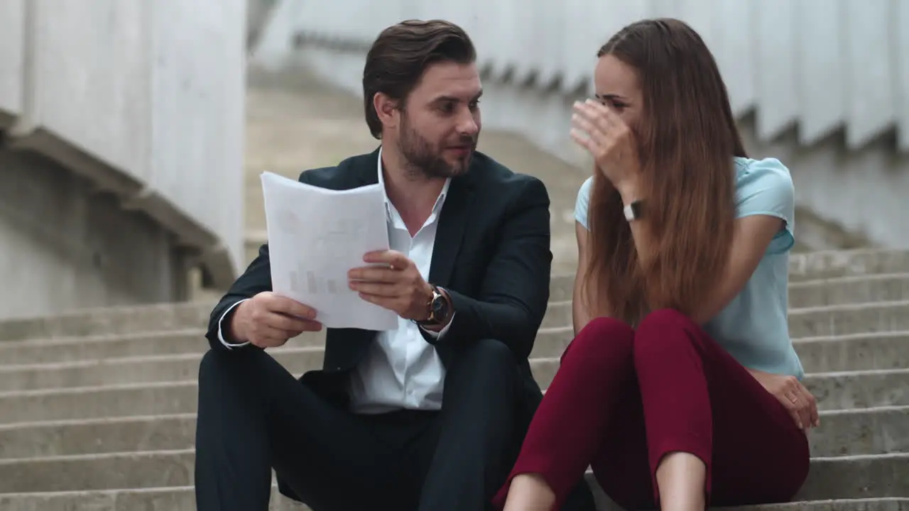 Joyful business man and business woman discussing results on documents in city