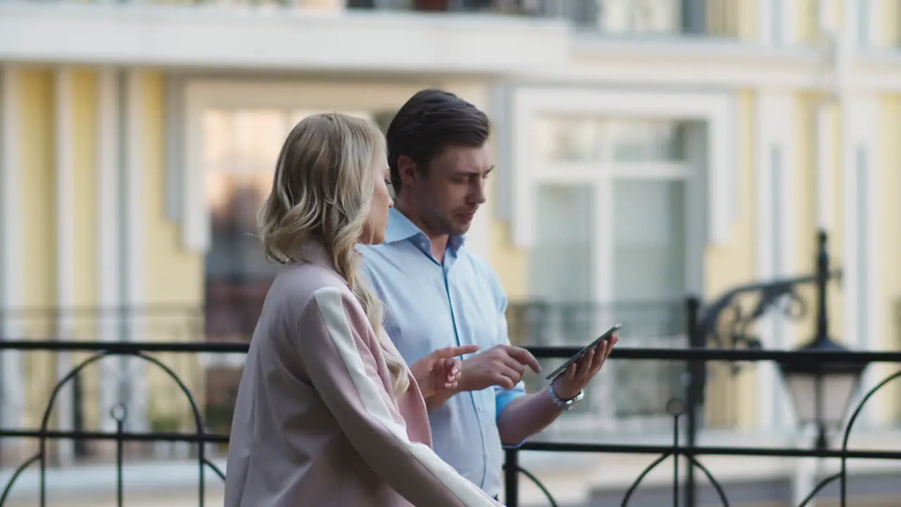 Serious business couple using tablet computer Business partners talking outdoor