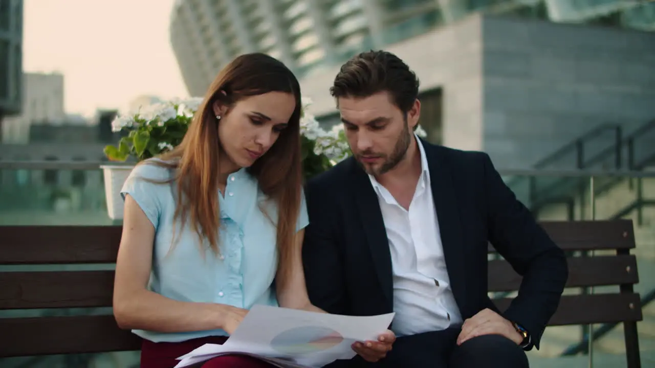 Business couple working with documents in city Professionals sitting on bench