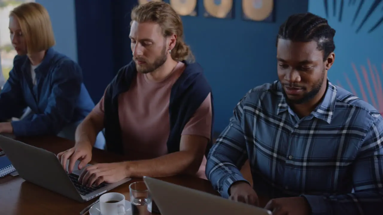 Multi ethnic business people typing on laptops in coworking