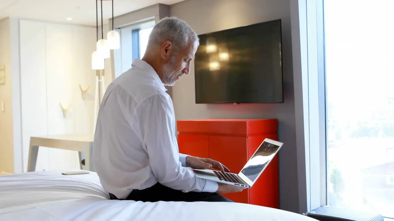 Businessman using laptop in hotel room 4k