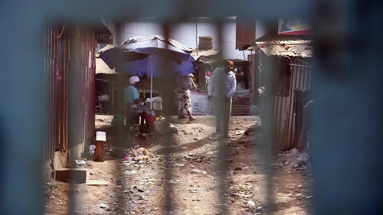 View of people in the street in Kibera through a gate