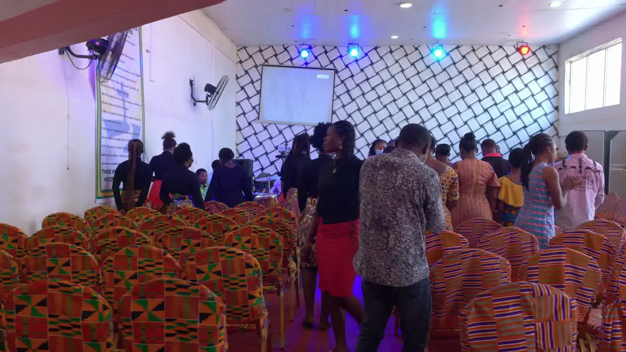 Happy African people dancing and clapping together inside rustic church