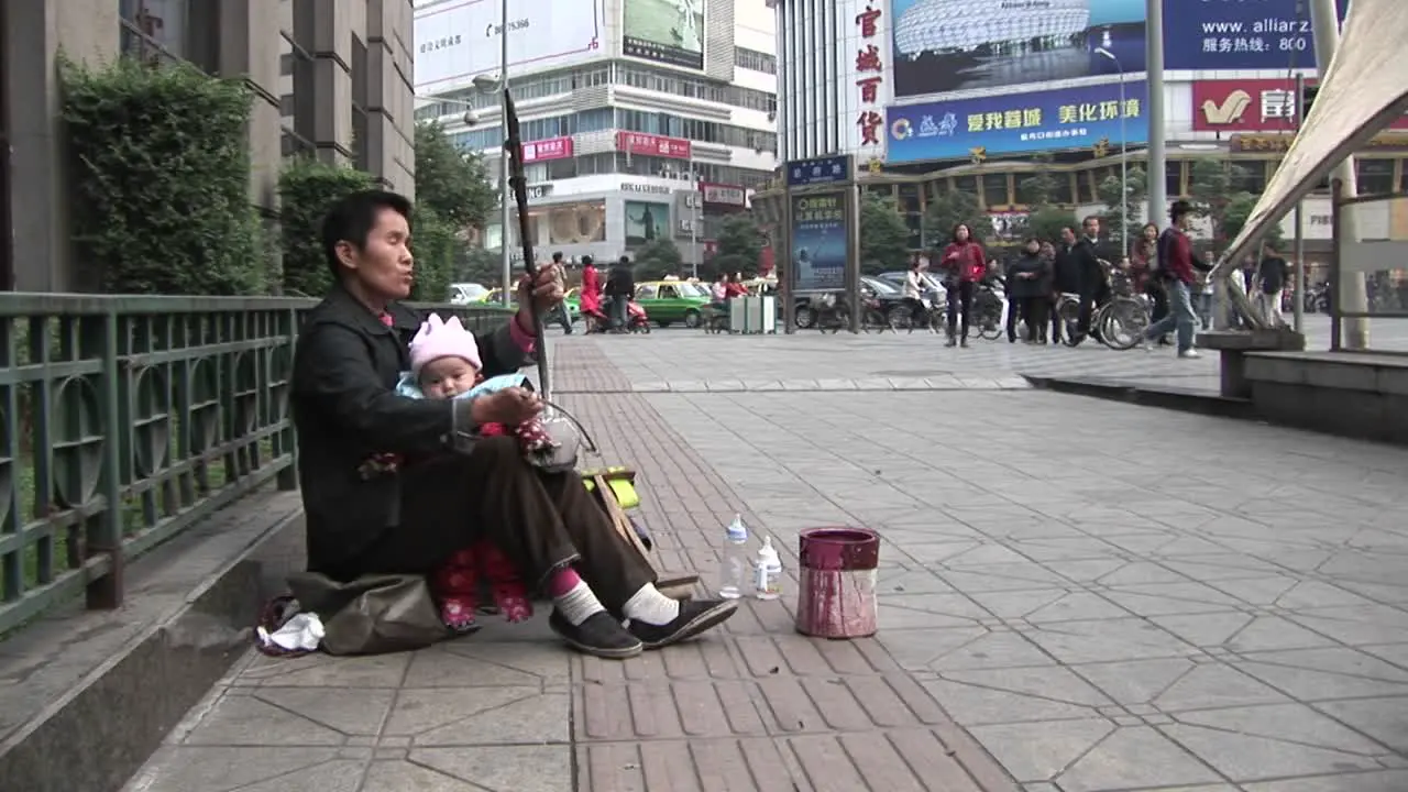 A blind man plays music along a street in modern China 1