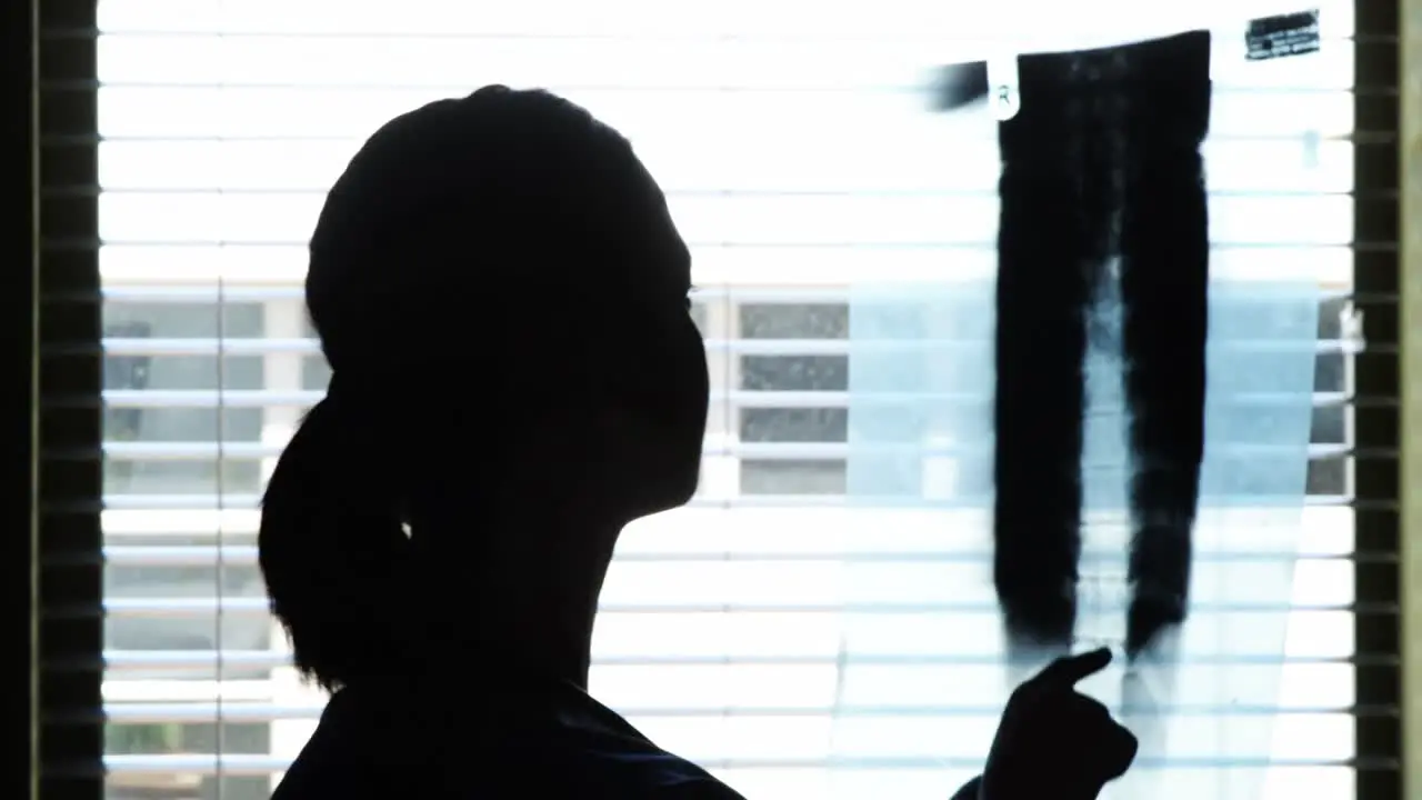 Silhouette of female doctor checking x-ray report