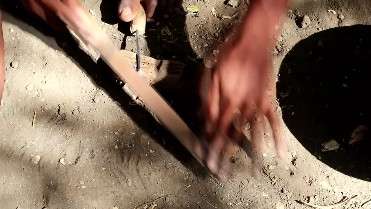 A black African person filing a tool using their hands and feet