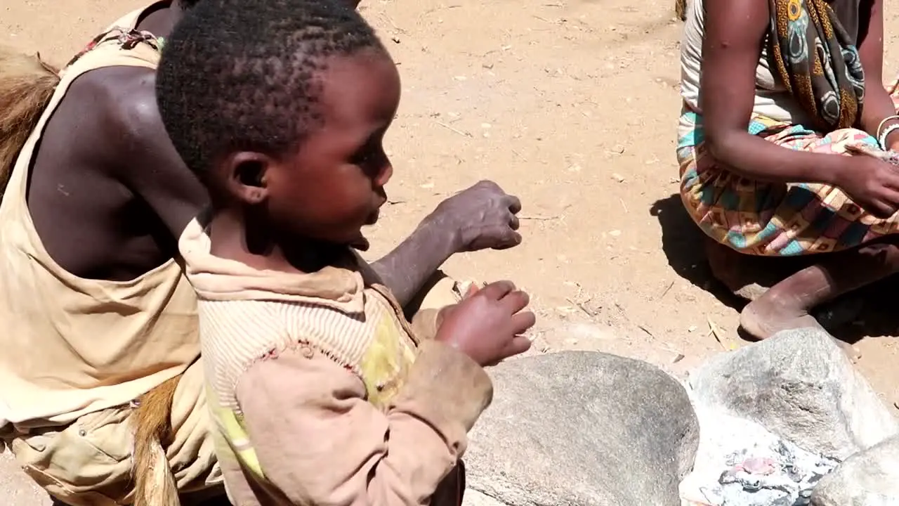 Young malnourished family in Africa with a small child eating a bird