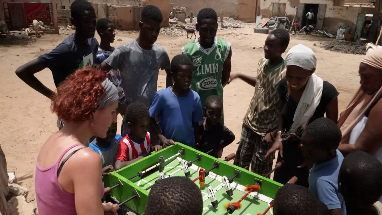 A white and a black women compete playing table soccer in the street of Nouakchott Mauritania