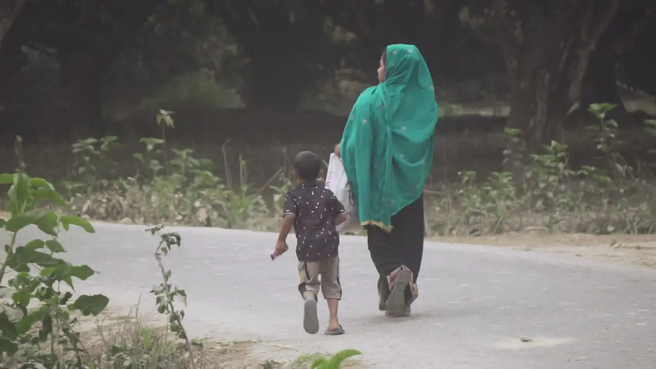 Woman along her kid walking along a village road