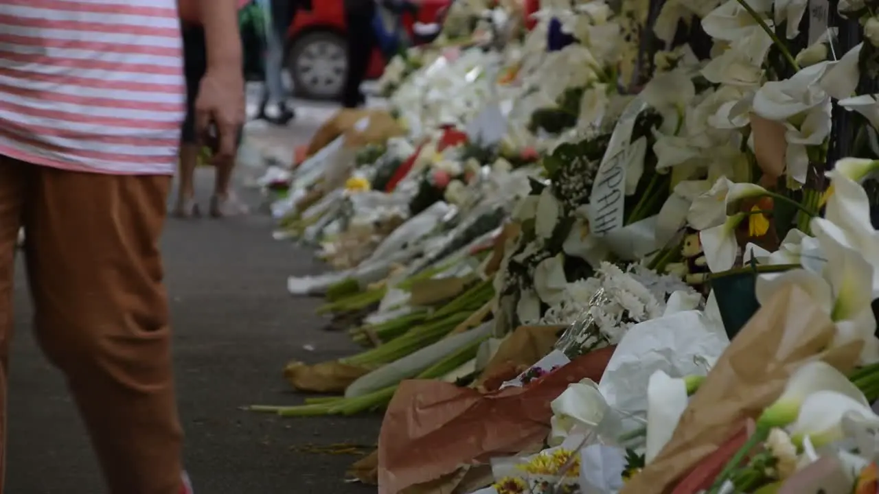 People walking past the wall of flowers near school shooting Belgrade Serbia