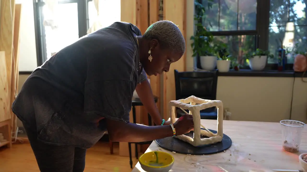 4k 60fps An african american artist sculpting a box in her studio during golden hour