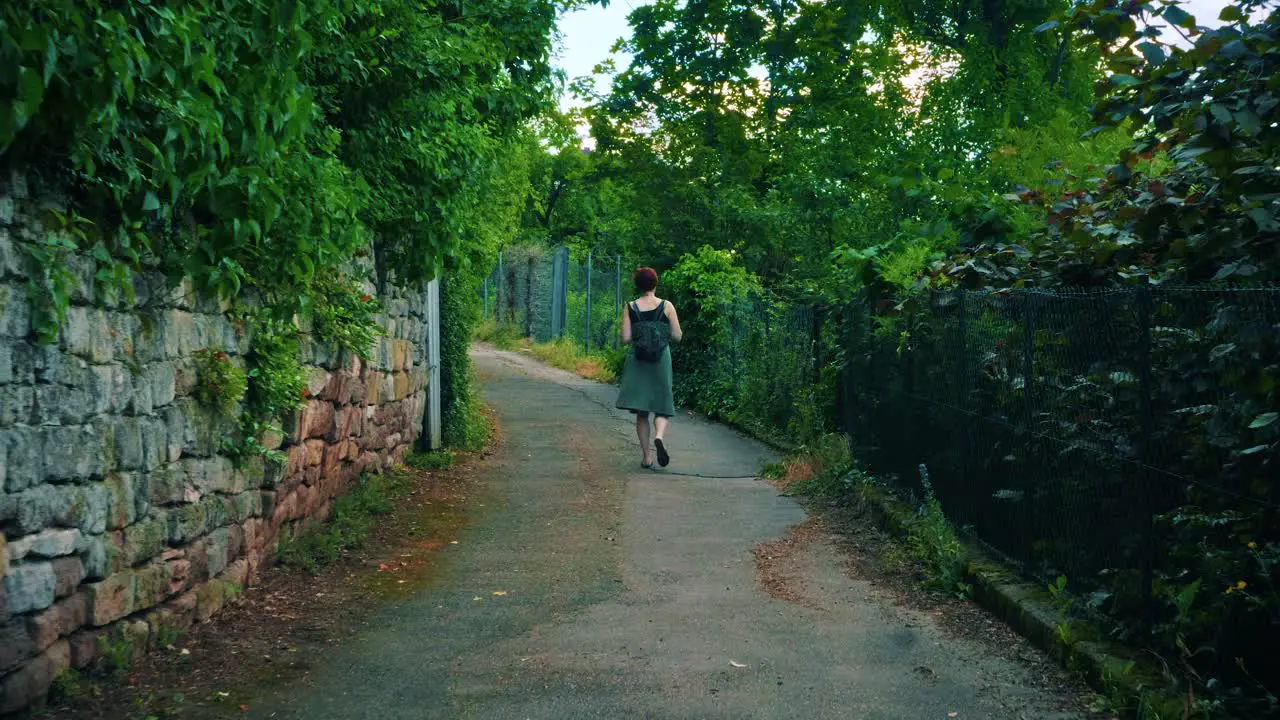 Back view of young caucasian woman walking on a rural dirt road in nature