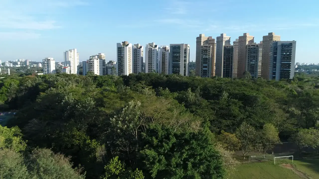 Drone with forward movement passing very close to many trees with nature around in public park sports health leisure in 4K resolution