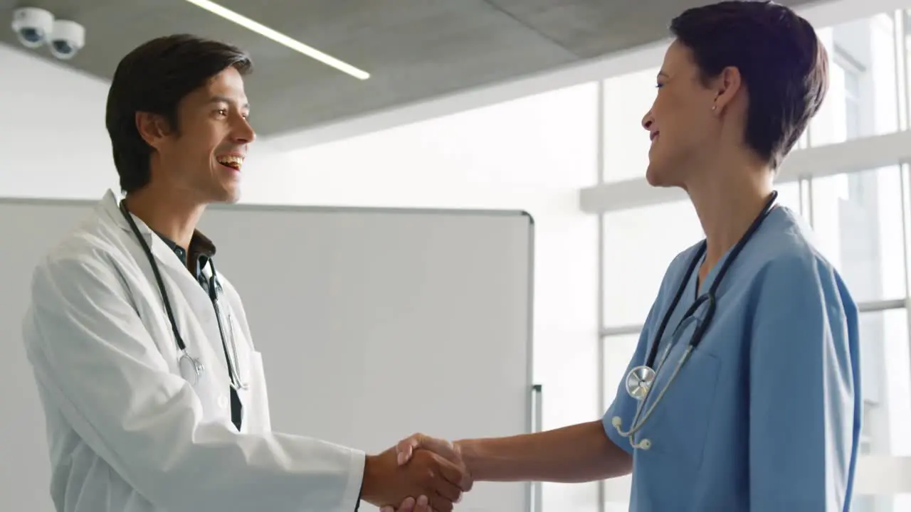 Two young doctors shaking hands in hospital 4k