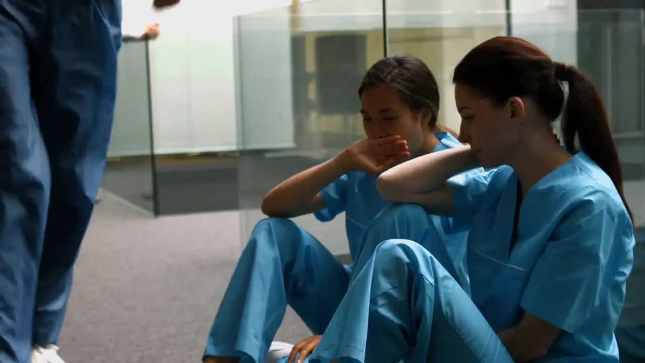 Sad nurses sitting on corridor