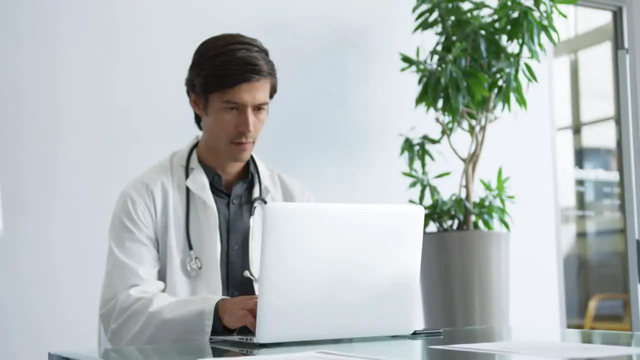 Young male doctor working on laptop 4k