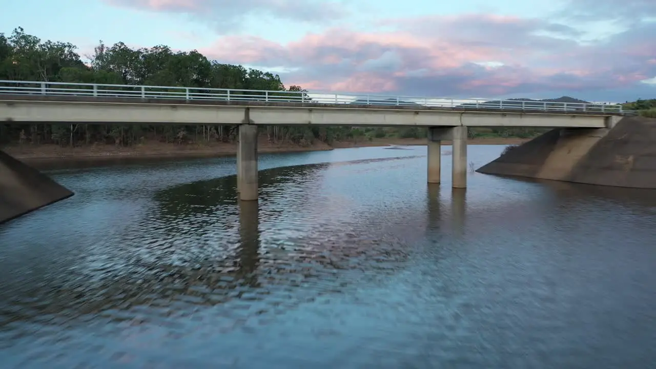 Drone descending and flying underneath a bridge on a lake near to Wivenhoe Dam