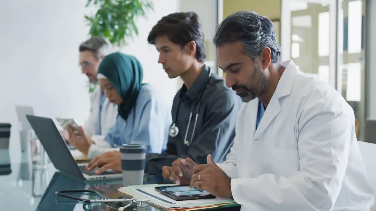 Doctor working with colleagues at table smiles to camera 4k