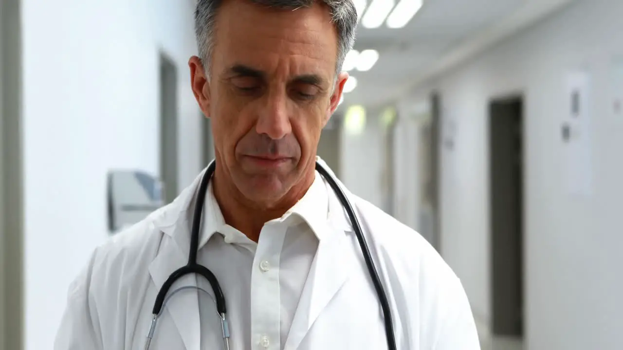 Smiling doctor using digital tablet in corridor