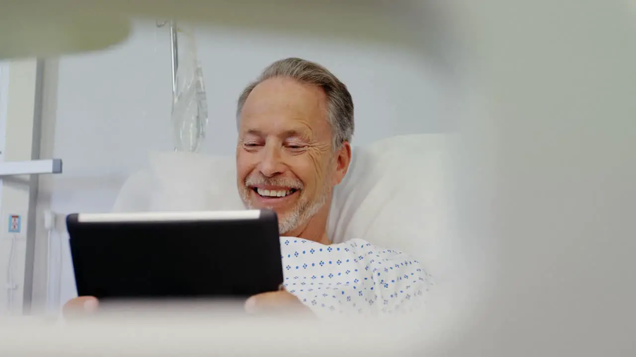 Patient using digital tablet on bed