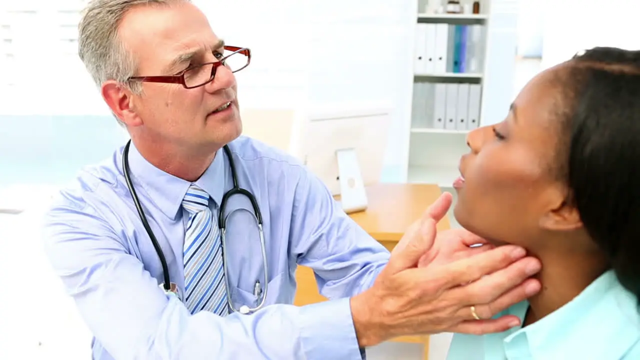 Doctor checking throat glands of his patient