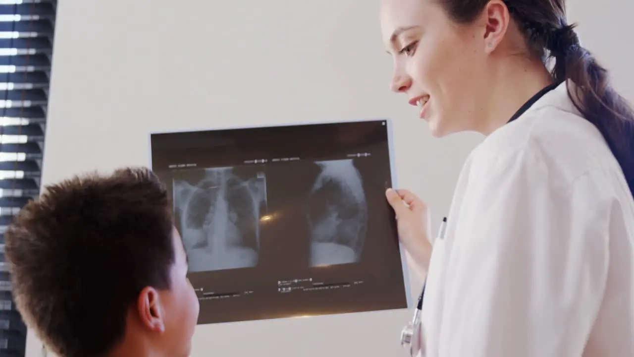 Female physiotherapist showing x-ray report to boy patient 4k