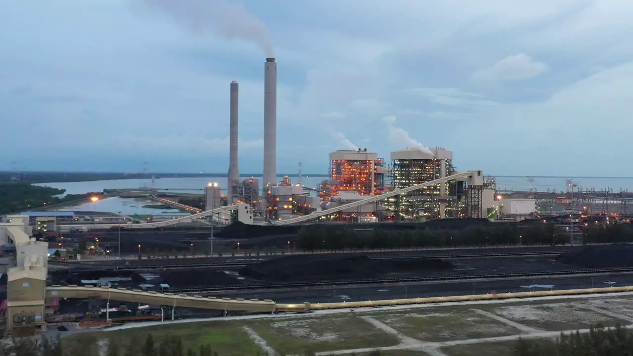 Fly around the parameter of the coalfield and industrial ultra-supercritical coal-fired power plant with smokes raising from chimney located at costal area of Manjung Perak Malaysia at dusk