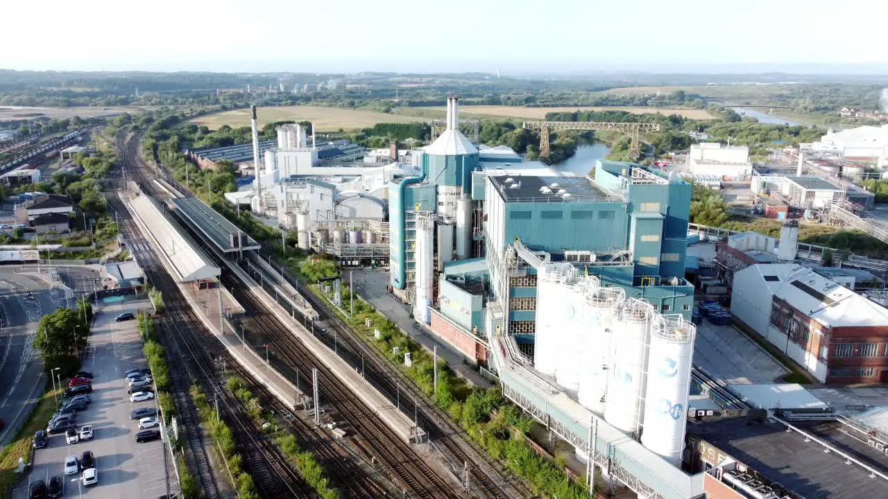 Industrial chemical manufacturing factory next to Warrington Bank Quay train tracks aerial view fast right orbit