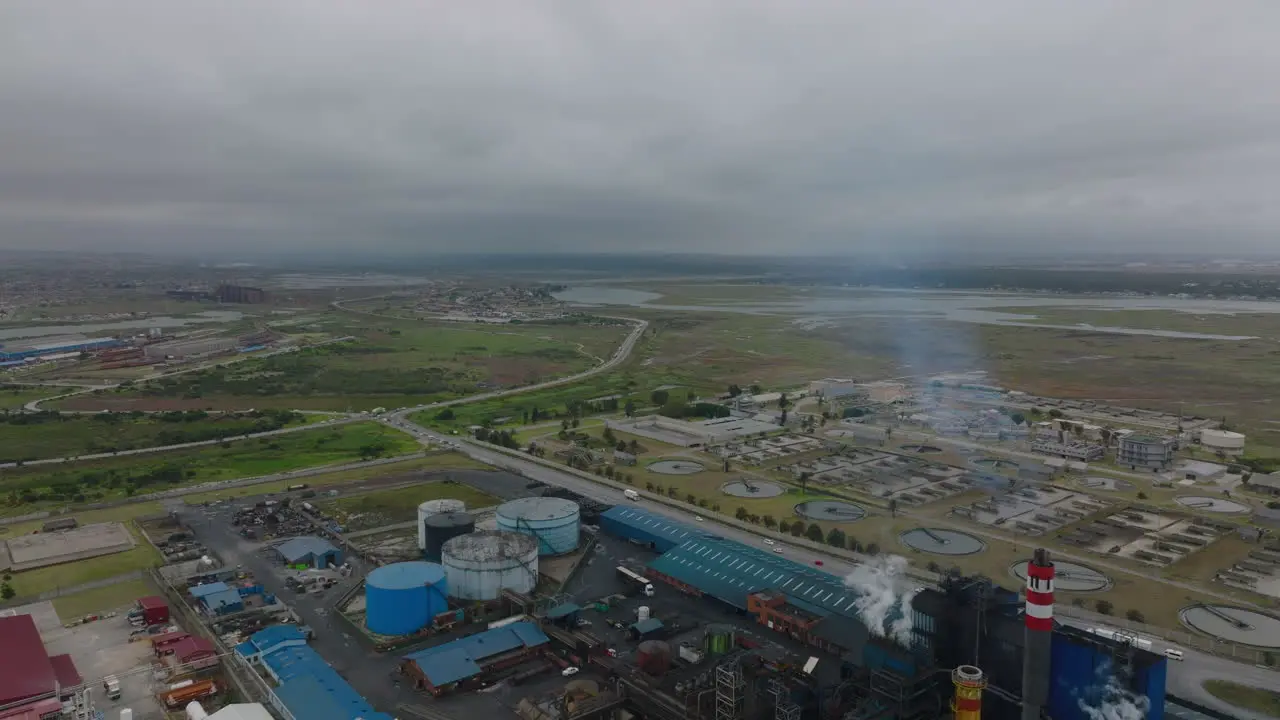 Aerial panoramic view of industrial sites in flat landscape Traffic on roads Tilt down on chemical factory Port Elisabeth South Africa