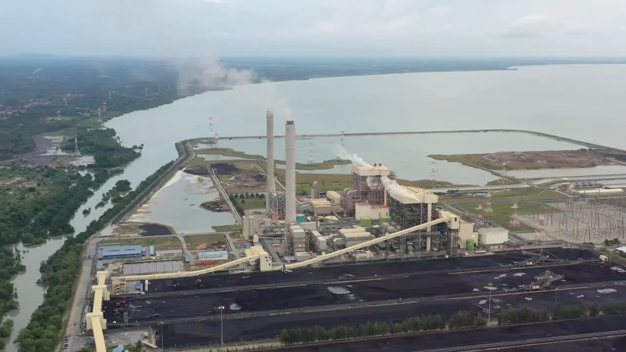 Drone fly around coastal coalfield industrial ultra-supercritical coal-fired power plant with smokes raising from chimney located at lekir bulk terminal jalan teluk rubiah manjung perak malaysia