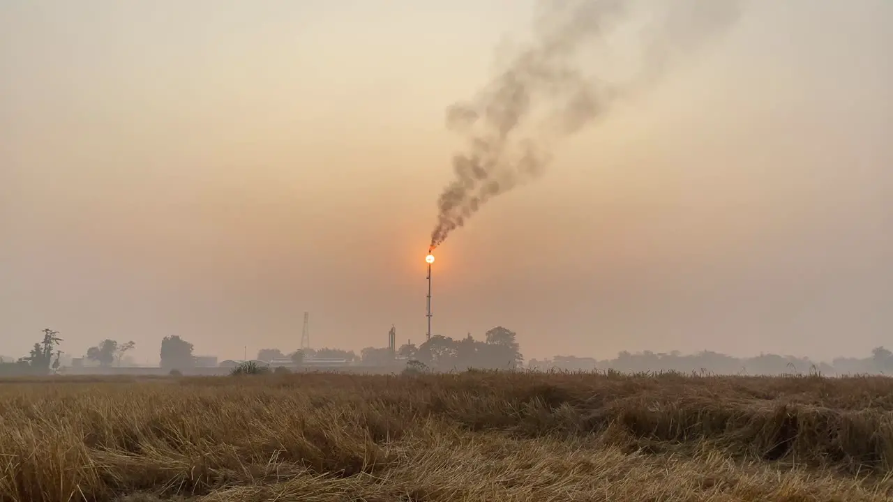 Static establisher view of industry area with Gas Plant tower releasing polluting fumes orange hazy sunset sky