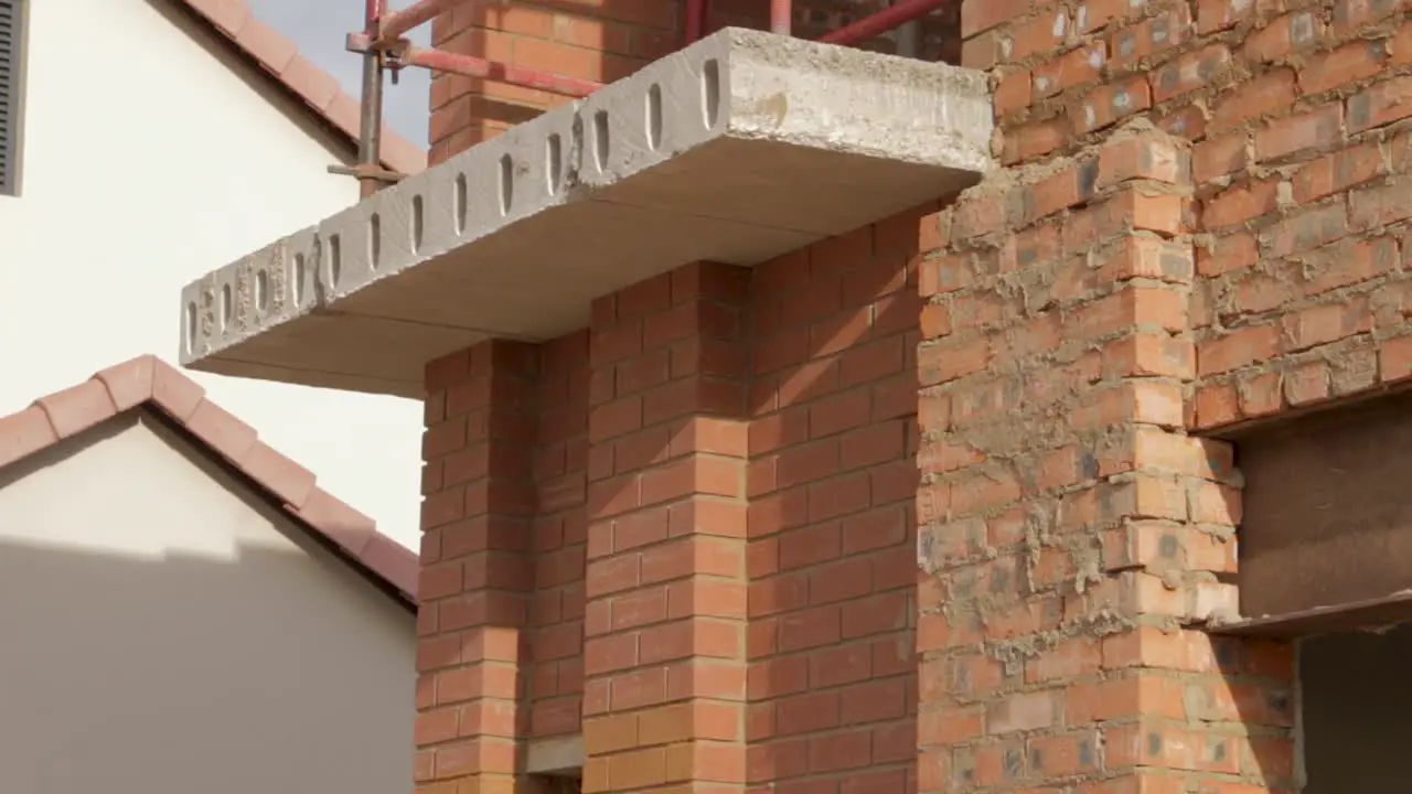 Tilt shot of new house construction site showing scaffolding and brick wall