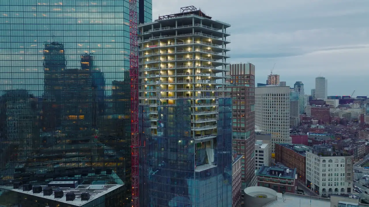 Slide and pan footage of construction new tall building Surrounding skyscrapers reflecting other buildings in glossy glass facade Boston USA