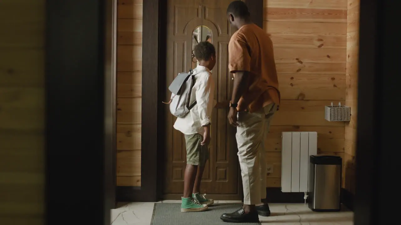 Loving Dad Helping His Son To Fasten Buttons On His Shirt Then Opening The Door And The Boy Leaving Home