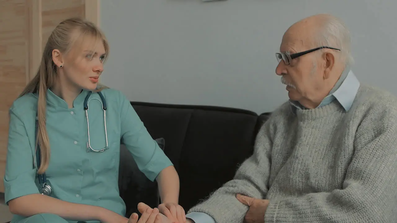 Young Caring Nurse Talking With Elderly Man